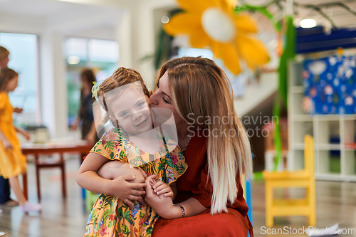 Image of A cute little girl kissing and hugs her mother in preschool