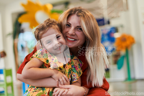 Image of A cute little girl kissing and hugs her mother in preschool