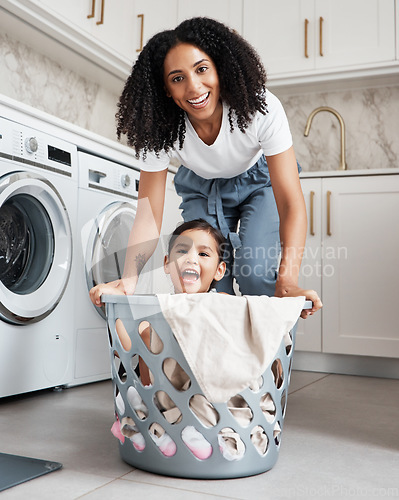 Image of Happy mother with her child in a washing basket at their home while doing laundry together. Happiness. housework and portrait of a young woman having fun with her girl kid while cleaning the house.