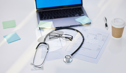 Image of Laptop, stethoscope and medical paperwork in a office for research, diagnosis or test results. Sticky notes, coffee and glasses on a desk for doctor to read healthcare documents in hospital or clinic