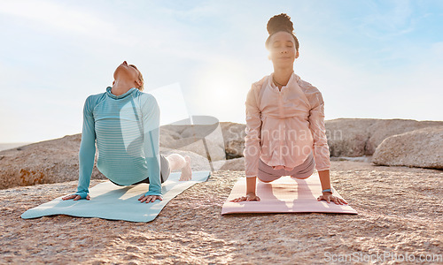 Image of Yoga, fitness and friends on the beach together for mental health, wellness or meditating in summer. Exercise, diversity or nature with a female yogi and friend practicing meditation outside