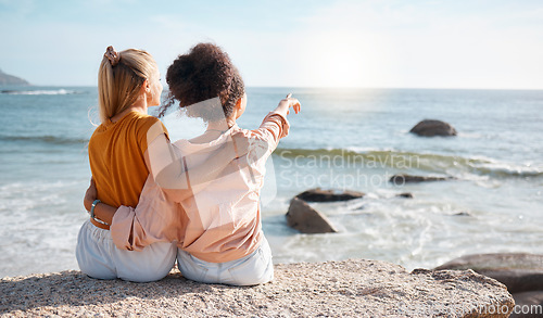 Image of Beach, rear view and women pointing at the sea for travel, sightseeing or fun on vacation against blue sky background. Back, friends and ladies relax at ocean with peace, freedom and bond in Miami