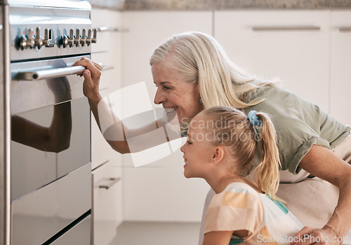 Image of Baking, kitchen and grandmother with a child by the oven watching the cake, cookies or pie bake. Happy, smile and senior woman with a girl kid cooking for dinner, party or event at their home.