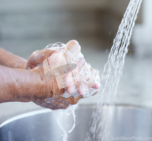 Image of Hands, washing and soap with water at sink for health, hygiene or self care to stop bacteria, virus or infection. Person, cleaning palm or skincare in home with faucet, wellness or closeup of bubbles