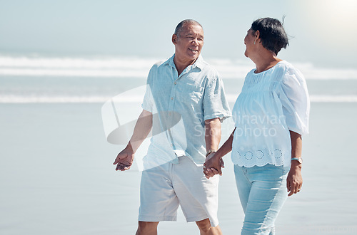 Image of Retirement, love and walking on the beach with a senior couple outdoor together on the sand by the ocean. Nature, walk or holding hands with a mature man and woman outside with the sea or water