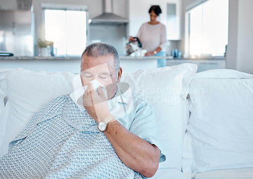 Image of Allergies, sick and senior man on sofa cleaning his nose for retirement, pension or elderly healthcare home. Virus, bacteria or allergy of old person on couch in house and woman in kitchen for help