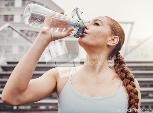 Image of Fitness, hydration and a sports woman drinking water outdoor in the city during cardio or endurance exercise. Runner, workout and hydrated with a female athlete training in an urban town for health