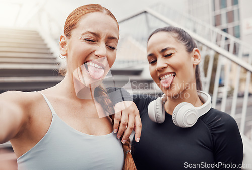 Image of Women, friends selfie and tongue in city for training, comic time or funny face with headphones in profile picture. Woman workout group, exercise photo or social media by stairs in metro with support