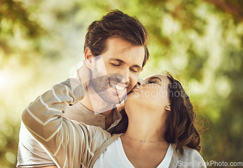 Image of Kiss, love and couple at park, smile and having fun time together outdoors. Valentines day, romance and care, affection and intimacy of happy man and woman kissing cheek on romantic date outside.