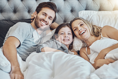 Image of Love, family and portrait in home bedroom, laughing at funny joke and bonding together. Care, comic and happy man, woman and girl, child or kid in bed, having fun and enjoying quality time in house.