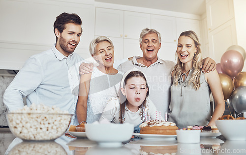 Image of Birthday, cake and big family with girl blowing out candles for wish, party or celebration event. Love, food and kid with happy father, mother and grandparents celebrating special day in home kitchen