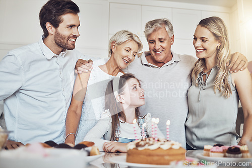 Image of Birthday party, cake and big family with girl in celebration of special event in house. Love, food and kid with happy father, mother and grandparents celebrating, talking and bonding in home kitchen.