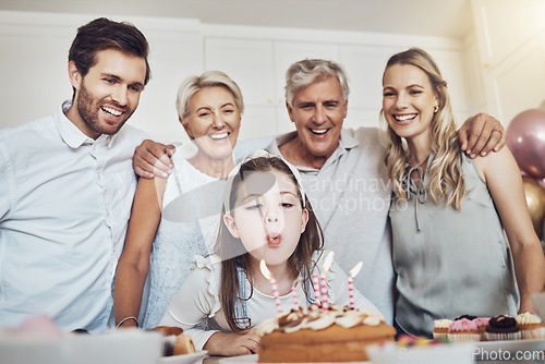 Image of Cake, birthday and big family with girl blowing out candles for wish, party or celebration event. Love, food and kid with happy father, mother and grandparents celebrating special day in home kitchen