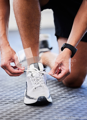 Image of Shoes, runner and man getting ready for training, exercise or running in sports sneakers, fashion and foot on floor. Feet of athlete or person tying his laces for cardio, fitness or workout in gym