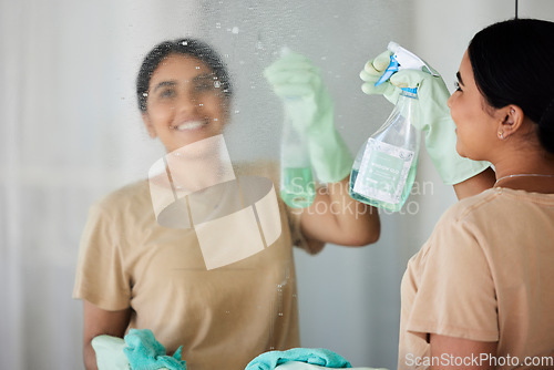 Image of Happy, woman and cleaning mirror with smile, spray bottle and soap, housekeeping in home or hotel. Housework, smudge and housekeeper or cleaner service washing dirt off glass reflection in apartment.