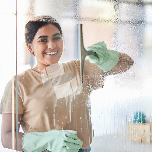 Image of Happy, smile and girl cleaning window with spray bottle and soap or detergent, housekeeper in home or hotel. Housework, smudge and woman or professional cleaner service washing off glass in apartment