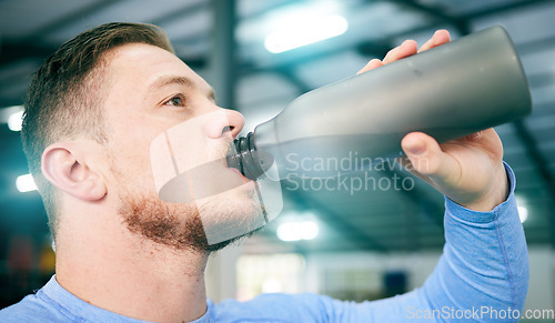 Image of Gym, fitness and man drinking water during training, exercise and intense cardio, serious and thirsty on blurred background. Hydration, athletic and male with bottle during workout at sports center