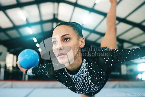 Image of Woman, gymnastics and stretching in balance with ball for training or practice at the indoor gym. Athletic female professional gymnast or acrobat in warm up stretch for exercise, workout or fitness