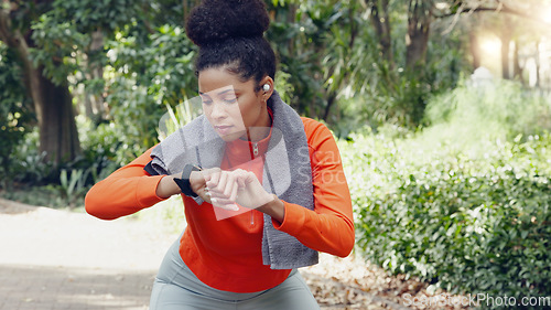 Image of Woman checking her pulse with a smart watch while on a health, fitness and wellness run in nature. Active girl on a jog for a cardio exercise in an outdoor park with an activity tracker and towel.