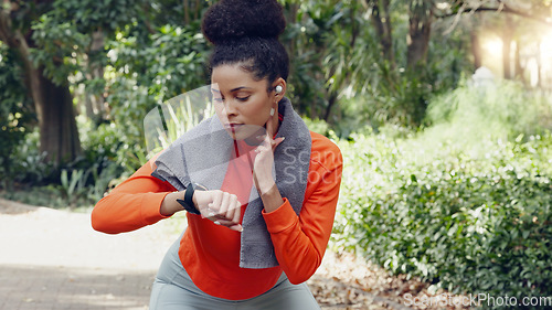Image of Woman checking her pulse with a smart watch while on a health, fitness and wellness run in nature. Active girl on a jog for a cardio exercise in an outdoor park with an activity tracker and towel.