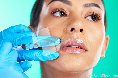 Image of Woman, face and hands with syringe for botox, plastic surgery or lip implants isolated on a studio background. Hand of doctor with needle injecting filler on female lips for facial cosmetic treatment