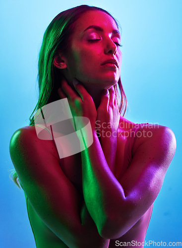 Image of Glowing skincare, hands or touch in neon lighting on isolated blue background with neck, body or skin. Beauty, model or fashion woman in creative fantasy green, pink or lights aesthetic in cosmetics