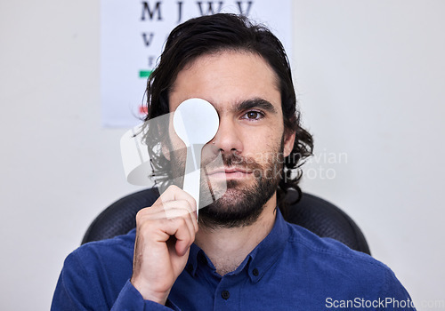 Image of Portrait, vision and spoon with a man patient at the optometrist for an eye exam testing his depth perception. Healthcare, medical and insurance with a male sitting in the office of an optician