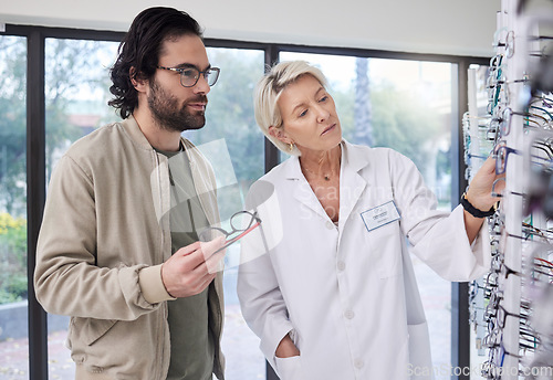 Image of Optometrist help customer with choice of glasses, vision and lenses in store. Optician, new frames and shelf of spectacles for eye care, consulting and retail shopping services for healthy eyesight