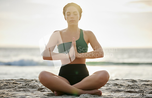 Image of Woman, yoga and meditation on the beach in sunset for spiritual wellness, zen or workout in the outdoors. Female yogi relaxing and meditating for calm, peaceful mind or awareness by the ocean coast