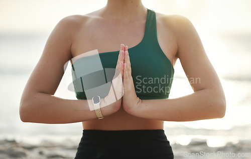 Image of Woman, hands and yoga in meditation on the beach for spiritual wellness, zen or workout in the outdoors. Hand of female yogi meditating or namaste for calm, peaceful mind or awareness by the ocean