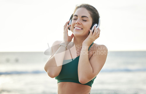 Image of Headphones, fitness and happy woman on beach for wellness, mental health and audio streaming on mockup. Sound, psychedelic or meditation podcast of person listening to music for peace by ocean or sea