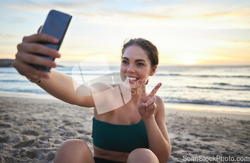 Image of Selfie, fitness and woman on beach peace sign, live streaming her workout, training or exercise results. Video call of sports, cardio person or gen z influencer relax on sand for runner break by sea