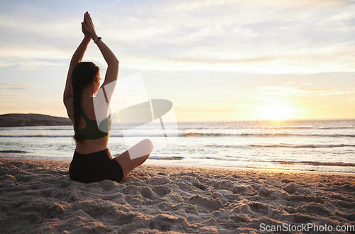 Image of Woman, yoga and meditation on the beach in sunset for spiritual wellness or zen workout outdoors. Female yogi relaxing or meditating in sunrise for calm, peaceful mind or awareness by the ocean coast