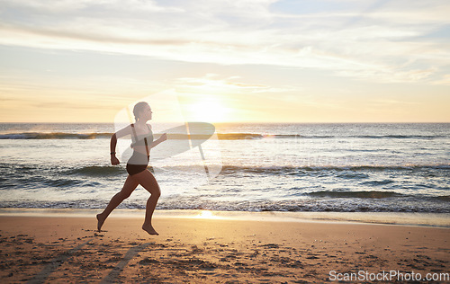 Image of Woman, fitness and runner on the beach in sunset for healthy cardio exercise, training or workout in the outdoors. Female running or exercising in sunrise for health and wellness by the ocean coast