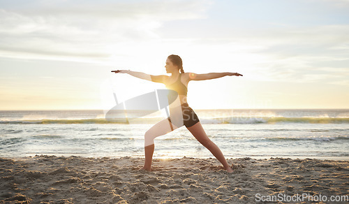 Image of Woman, yoga and meditation on the beach for zen, spiritual wellness or workout in the sunset outdoors. Female yogi meditating in warrior pose for calm, peaceful mind or awareness by the ocean coast