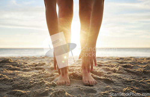 Image of Stretching, fitness and feet of woman at beach for relax, wellness and yoga training. Sunset, health and peace with girl and warm up touching toes in sand for workout, energy and pilates exercise