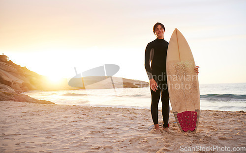 Image of Surfer, portrait and man with surfboard at the sea, beach and ocean in sunset or the morning with mockup space. Young, ready and male in swimsuit on a sunny surf day on the sand, shore and water