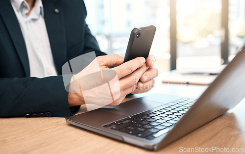 Image of Hands, phone and laptop with a business man doing research in his office while typing a text message. Mobile, communication and networking with a male manager or employee reading an email at work