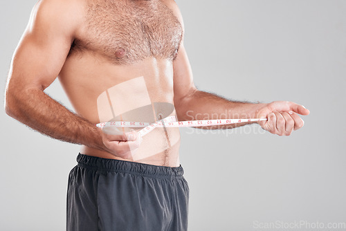 Image of Health, fitness and man with measuring tape on waist, healthy diet and exercise for body care. Sports, nutrition and stomach, tracking weight loss and six pack progress isolated on grey background.