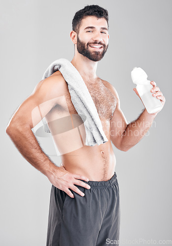 Image of Portrait, exercise and man with towel, water bottle and training on grey studio background. Canada, face and happy male athlete with liquid after practice, healthy lifestyle and workout for wellness