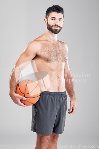 Image of Sport, fitness and portrait of man with basketball and smile, topless and isolated on grey background. Exercise, motivation and ball sports coach or personal trainer with workout mindset in studio.