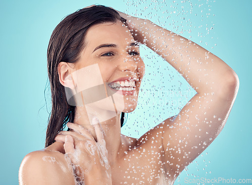 Image of Water splash, skincare and face of woman in shower in studio isolated on a blue background. Beauty, thinking and happy young female model washing, cleaning or bathing for hygiene, wellness and health