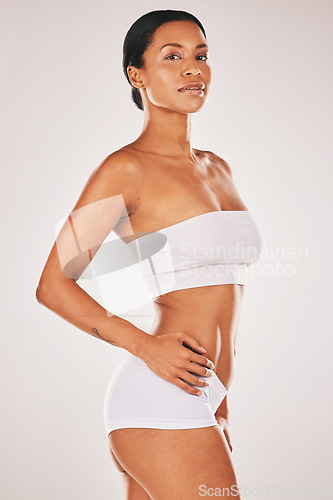 Image of Portrait, natural and body with a model black woman in studio on a gray background for beauty or wellness. Fitness, bodycare and underwear with an attractive young female posing to promote health