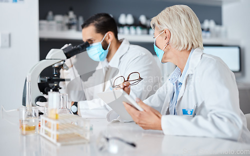 Image of Scientist teamwork, lab and covid 19 vaccine research for pharma company with mask, ppe and tablet. Man, woman and science with microscope analysis, advice and goals to stop global virus with results