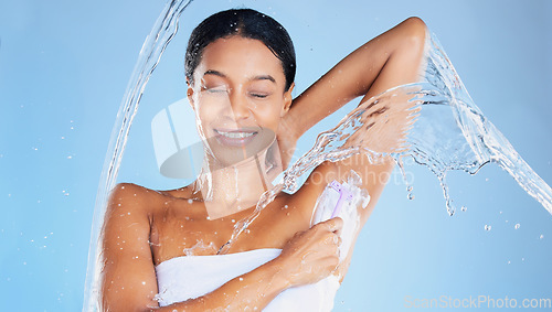 Image of Black woman, water splash or shaving underarms on blue background in relax grooming, body hair removal or healthcare wellness. Beauty model, happy or wet in armpit razor cream for skincare cleaning