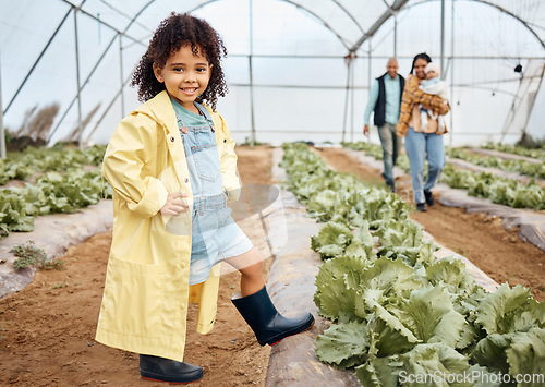 Image of Kid, happy or girl in farming portrait, akimbo or hands on hips in greenhouse, agriculture land or sustainability field pride. Smile, child or learning gardening in countryside nature or lettuce agro