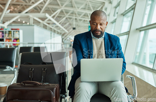Image of Black man, laptop and luggage at airport for business travel, trip or working while waiting to board plane. African American male at work on computer checking online schedule times for flight delay