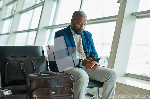 Image of Black man, phone and luggage at airport for business travel, trip or communication waiting for flight. African American male traveler chatting or checking plain times, schedule or delay on smartphone