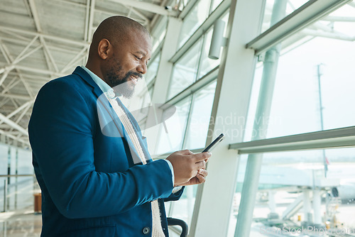 Image of Black man, phone and chatting at airport for business travel, trip or communication waiting for flight. African American male smile for conversation, schedule or checking plain times on smartphone