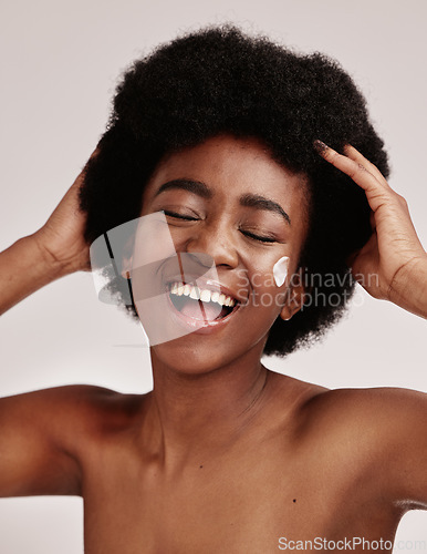 Image of Skincare, beauty and black woman with afro and cream on face, smile and advertising luxury skin product promotion. Dermatology, cosmetics and spa facial for happy model isolated on studio background